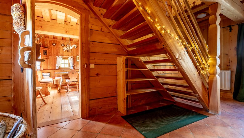 Stiegenaufgang, © Wiener Alpen / Christian Kremsl Holztreppe in einem Haum mit Holzvertäfelung mit Lichterkette dekoriert.