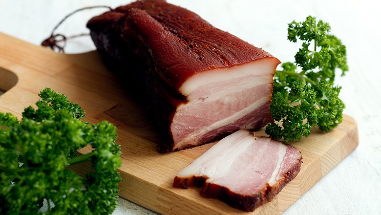 Speck, © Sooo gut schmeckt die Bucklige Welt/ Viktoria Kornfeld Ein Stück Speck auf einem Holzbrett mit Petersilie.