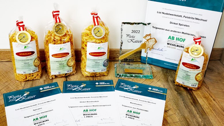 Pasta Kaiser 2022, © Familie List Verschiedene Nudelpackungen und Auszeichnungen auf einem Holzboden.