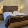 Doppelzimmer, © Hotel Post Hönig Ein gemütliches Doppelzimmer mit großem Bett, dekoriert mit brauner Bettwäsche und Handtüchern. An der Wand sind geometrische Muster.