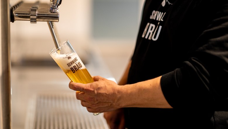 Schwarzbräu, © Wiener Alpen, Christian Kremsl Eine Person zapft Bier in ein Glas mit der Aufschrift "Schwarzbräu".