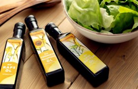 Öle, © Sooo gut schmeckt die Bucklige Welt/Viktoria Kornfeld Drei verschiedene Öle liegen auf einem Holztisch neben einer Schüssel mit grünem Salat.