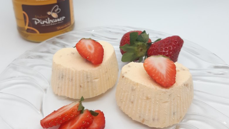 Geeiste Honigherzen, © Imkerei Piribauer Zwei geeiste Honigherzen auf Glasteller, ganiert mit Erdbeeren. Im Hintergrund ein Honigglas.