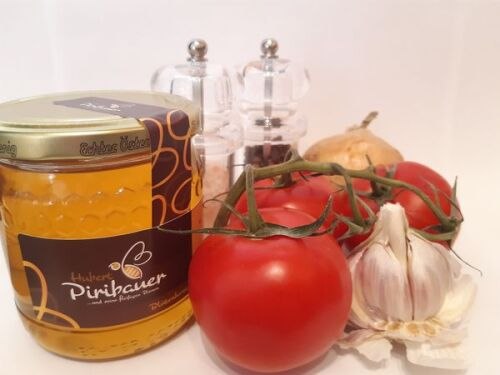 Tomatensuppe, © Imkerei Piribauer Tomaten, Knoblauch, ein Honigglas, Salz- und Pfefferstreuer vor weißem Hintergrund.