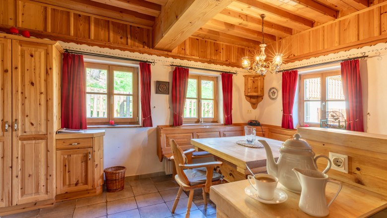 Essbereich, © Wiener Alpen / Christian Kremsl Essbereich in traditionellem Stil mit Holzmöbeln und roten Vorhängen.
