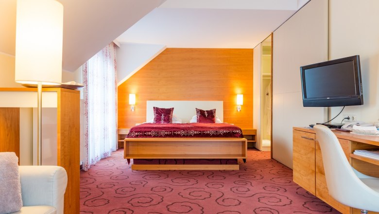 Suite, © Vitalzeit Hotel Weber Hotelzimmer mit Doppelbett, Schreibtisch und Fernseher.