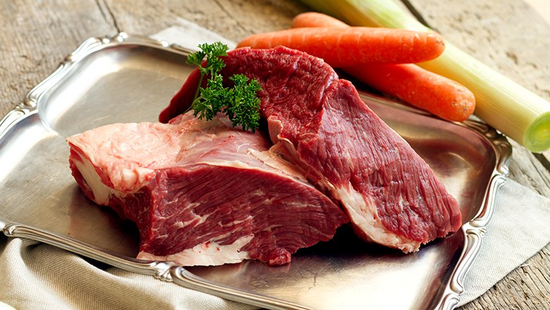 Frischfleisch, © Sooo gut schmeckt die Bucklige Welt/ Viktoria Kornfeld Zwei Stück rohes Fleisch auf einem silbernen Tablett auf einem Holztisch. Daneben Kartotten und Lauch.