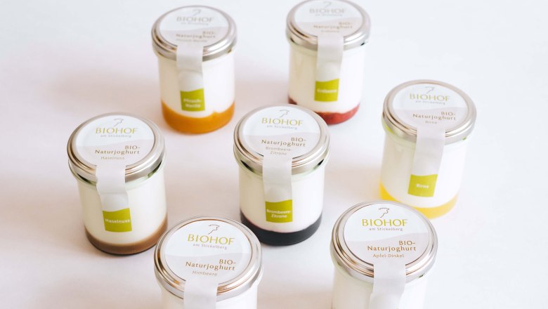 Joghurt Biohof am Stickelberg, © Anni Lechner Fotografie Sieben Gläser mit Naturjoghurt, jeweils mit unterschiedlichen Fruchtspiegeln, vor weißem Hintergrund.