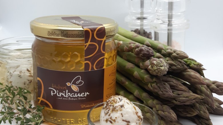 Ein Honigglas, Gläser mit Ziegenkäse, Spargel, Salz- und Pfefferstreuer vor weißem Hintergrund.