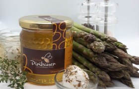 Ein Honigglas, Gläser mit Ziegenkäse, Spargel, Salz- und Pfefferstreuer vor weißem Hintergrund.