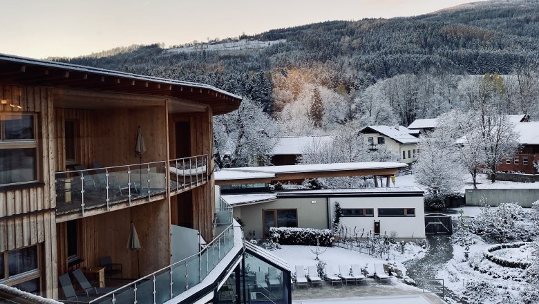 Winterliche Landschaft mit schneebedeckten Gebäuden und Bäumen in den Bergen.