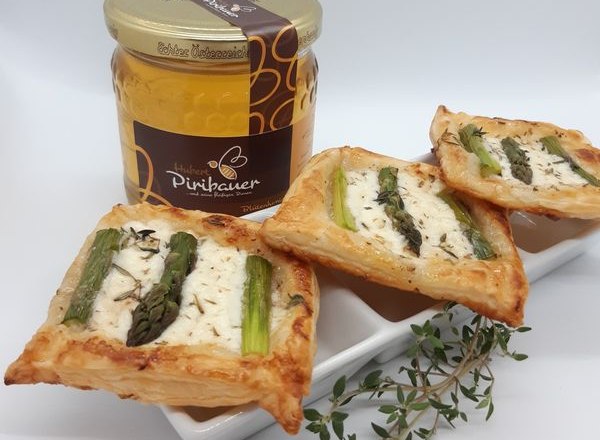 Drei Spargeltartelettes auf weißem Teller, daneben Thymian und ein Honigglas.