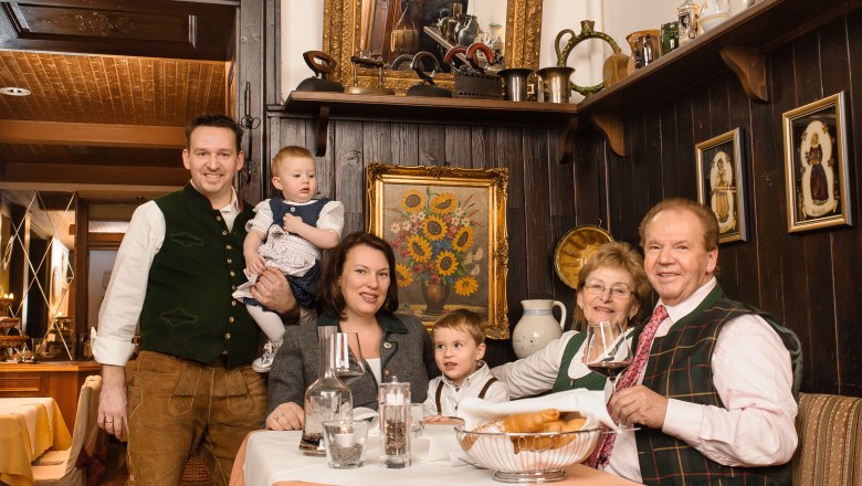 Eine Familie in traditioneller Kleidung sitzt an einem Tisch in einem rustikalen Restaurant.