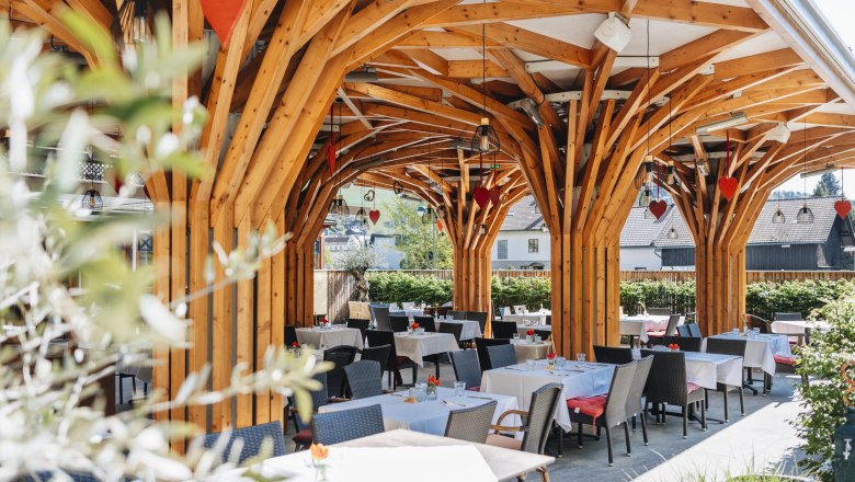 Moderner Gastgarten mit Holzkonstruktion und gedeckten Tischen.