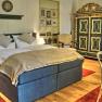 Elegantes Schlafzimmer mit Doppelbett, antikem Schrank und roten Teppichen.
