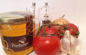 Tomaten, Knoblauch, ein Honigglas, Salz- und Pfefferstreuer vor weißem Hintergrund.