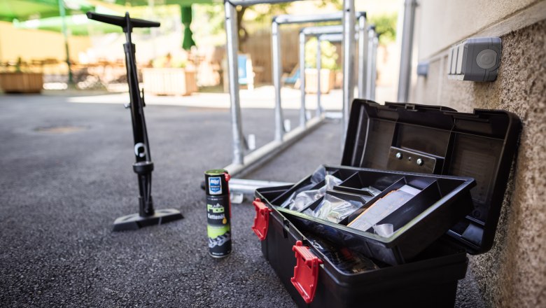 Fahrradwerkzeug, Ketten&ouml;l und Pumpe neben Fahrradst&auml;ndern im Freien.