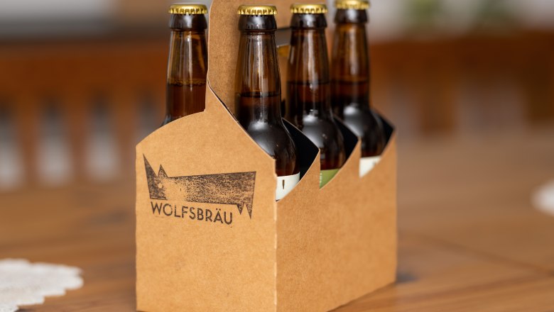 Ein Bierträger aus braunem Karton mit sechs Bierflaschen von Wolfsbräu.