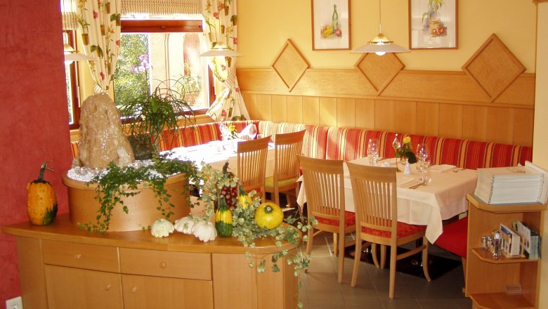 Gemütliches Restaurant mit Holzmöbeln, dekoriert mit Kürbissen und Pflanzen.