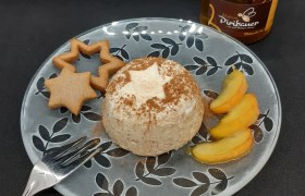 Ein Teller mit Lebkuchenmousse, Lebkuchen und Apfelspalten, daneben ein Honigglas und eine Gabel.