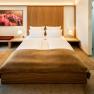 Modern eingerichtetes Hotelzimmer mit Doppelbett, Nachttischen, Lampen und einem Bild an der Wand.