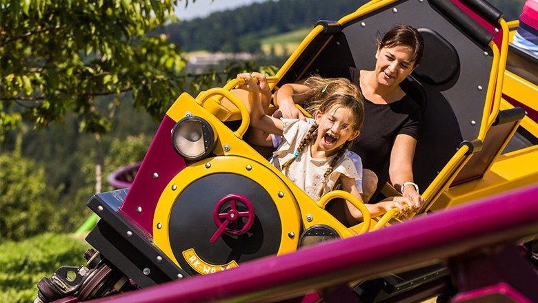 Eine Frau und ein Kind im Waggon einer Achterbahn im Eis-Greissler Erlebnispark.